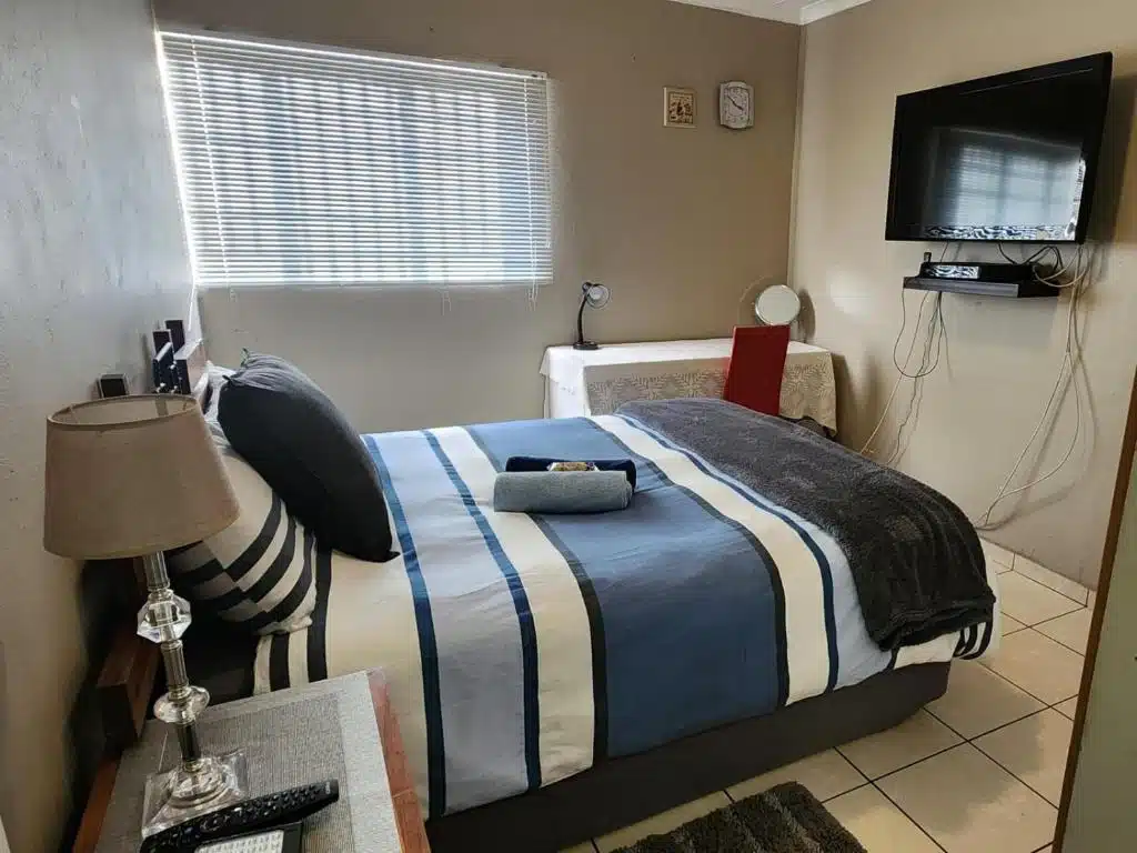 Secunda Accommodation Near Kinross Golf Club & Lake Umuzi Bedroom with striped bedding and wall-mounted TV